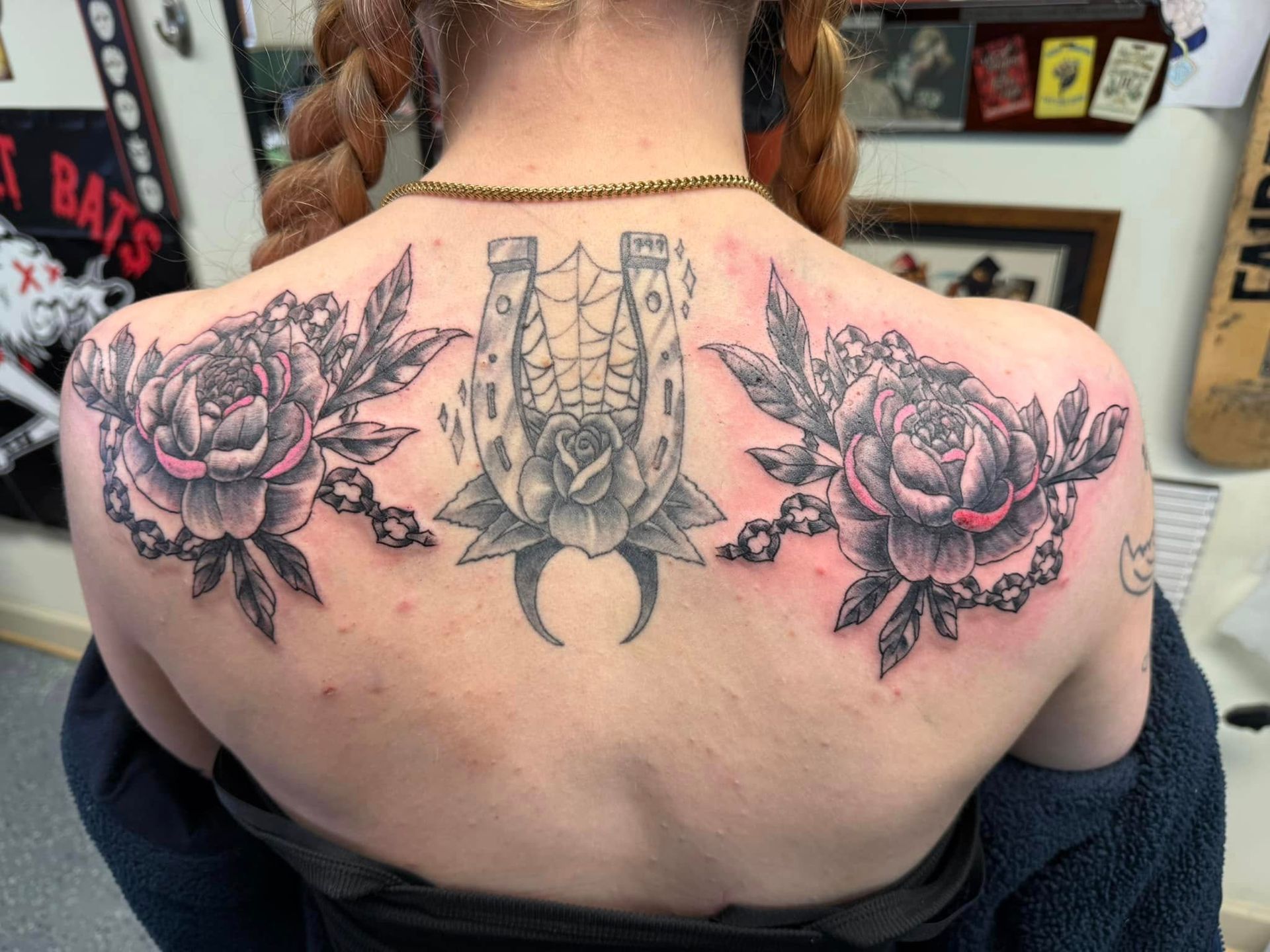 Back view of a person with a large floral tattoo across the upper back and shoulders
