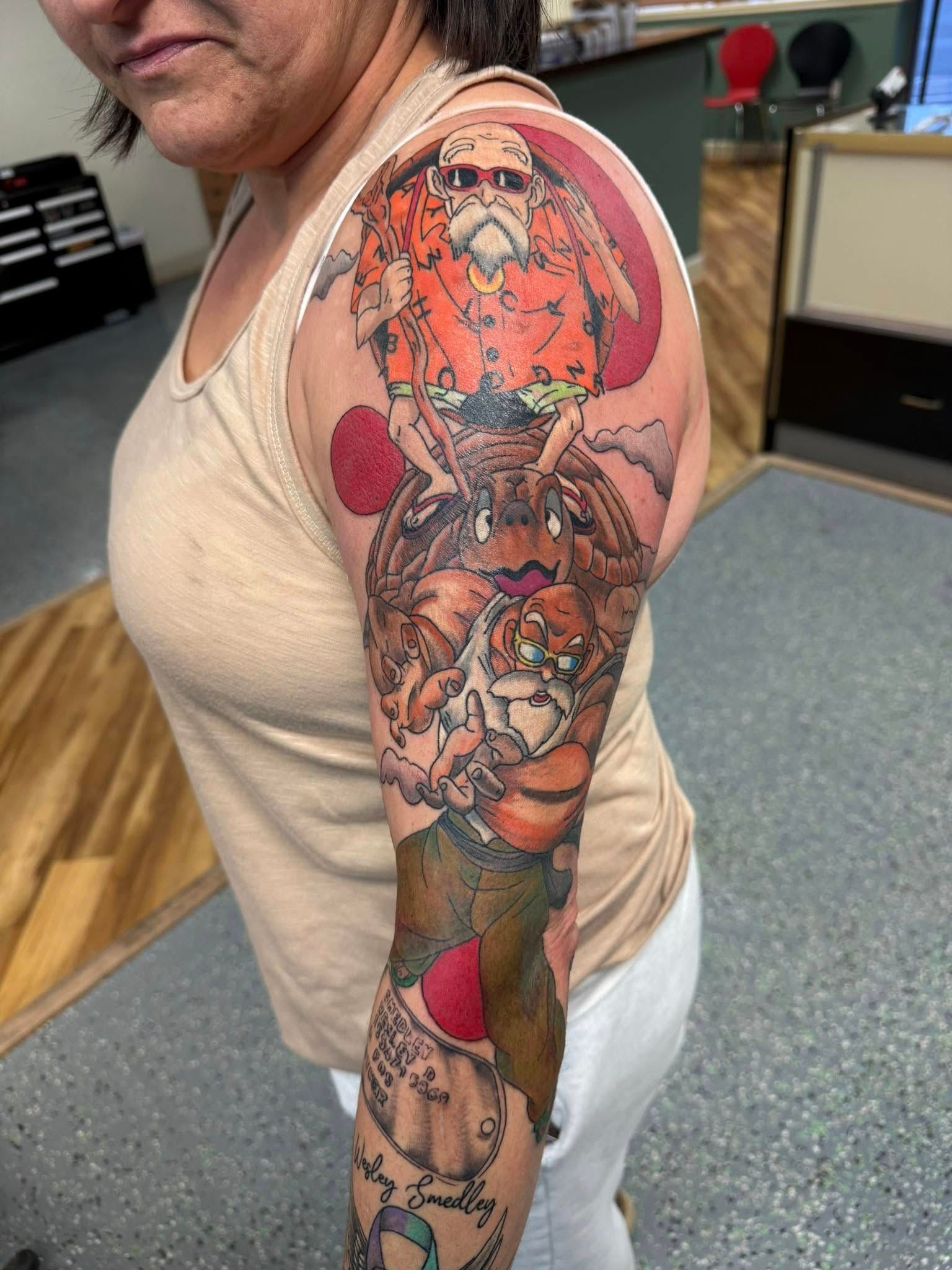 Person showing a colorful tiger tattoo sleeve on their arm in a tattoo studio