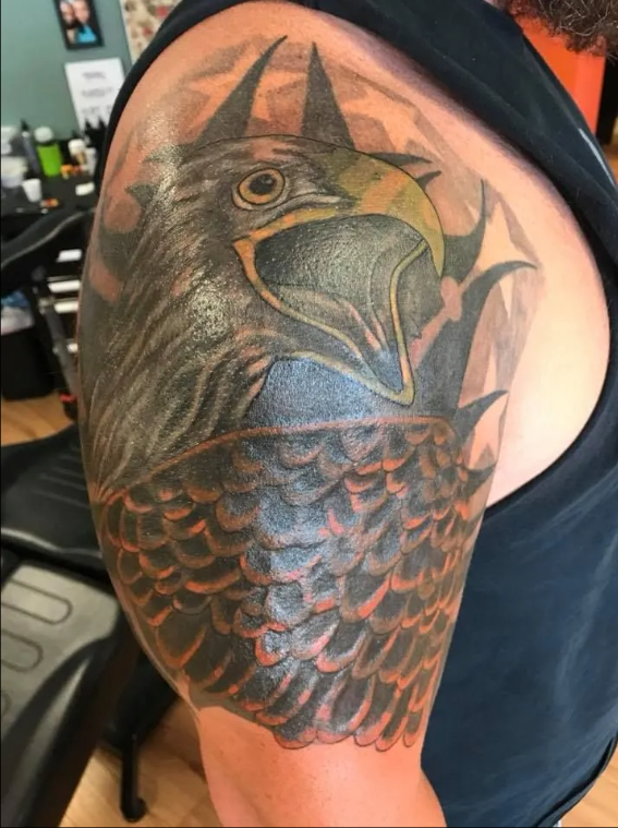Tattoo of a dark, horned female face with flowing hair on a person’s forearm