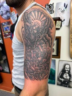 Arm tattoo of a vintage car dashboard, shown on a person in a black sleeveless shirt, in a tattoo studio