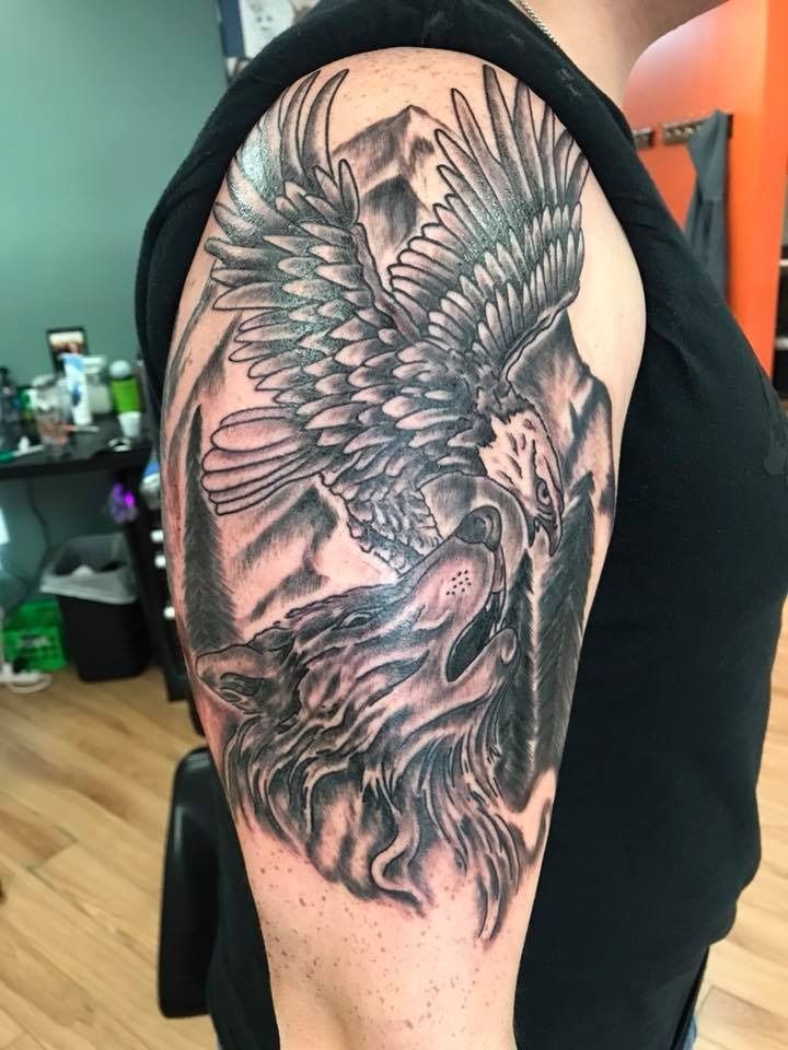 Black and gray phoenix tattoo on an upper arm, with detailed feathers and wings.