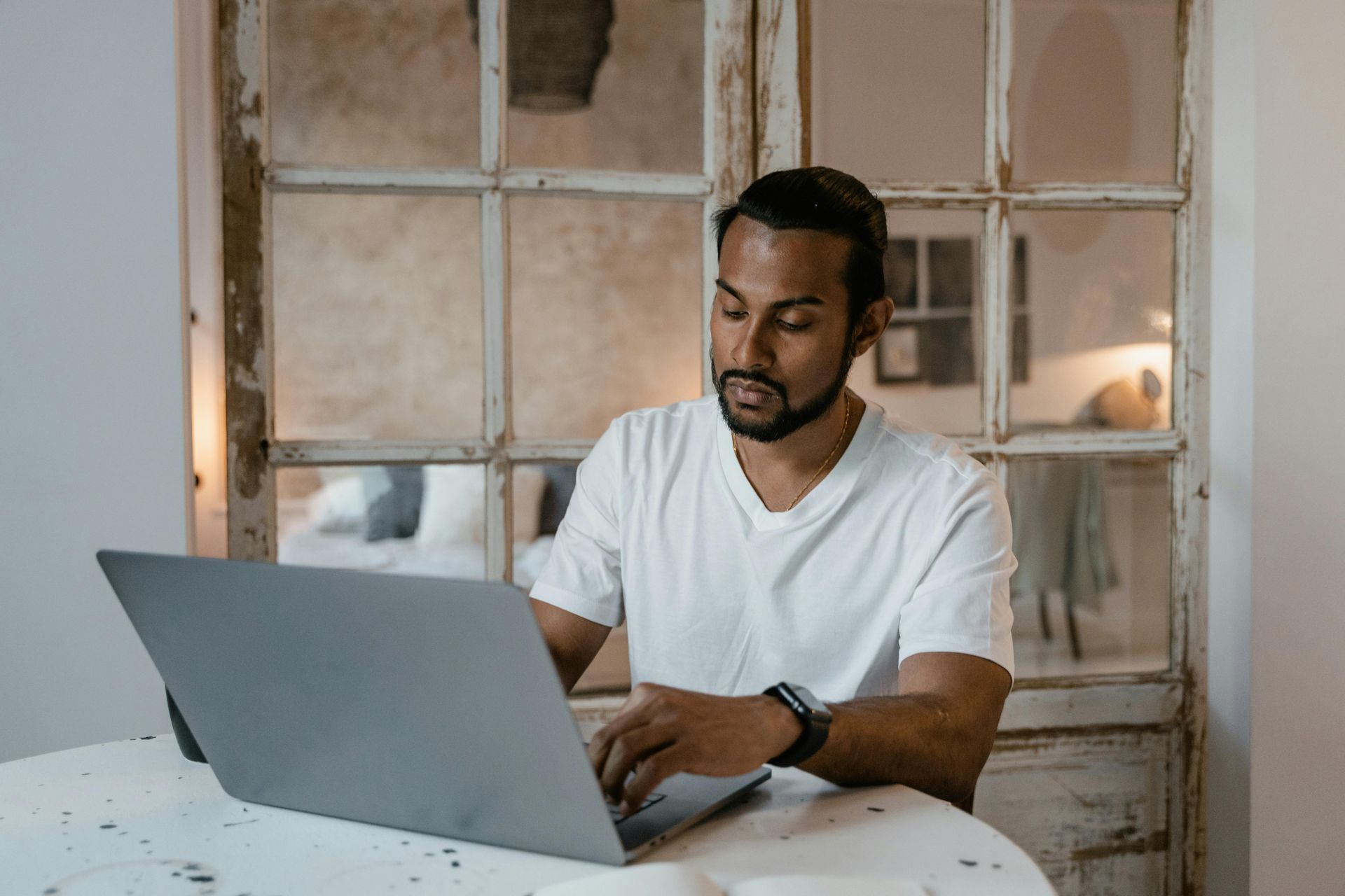 Person using a laptop at a table in a bright, rustic room