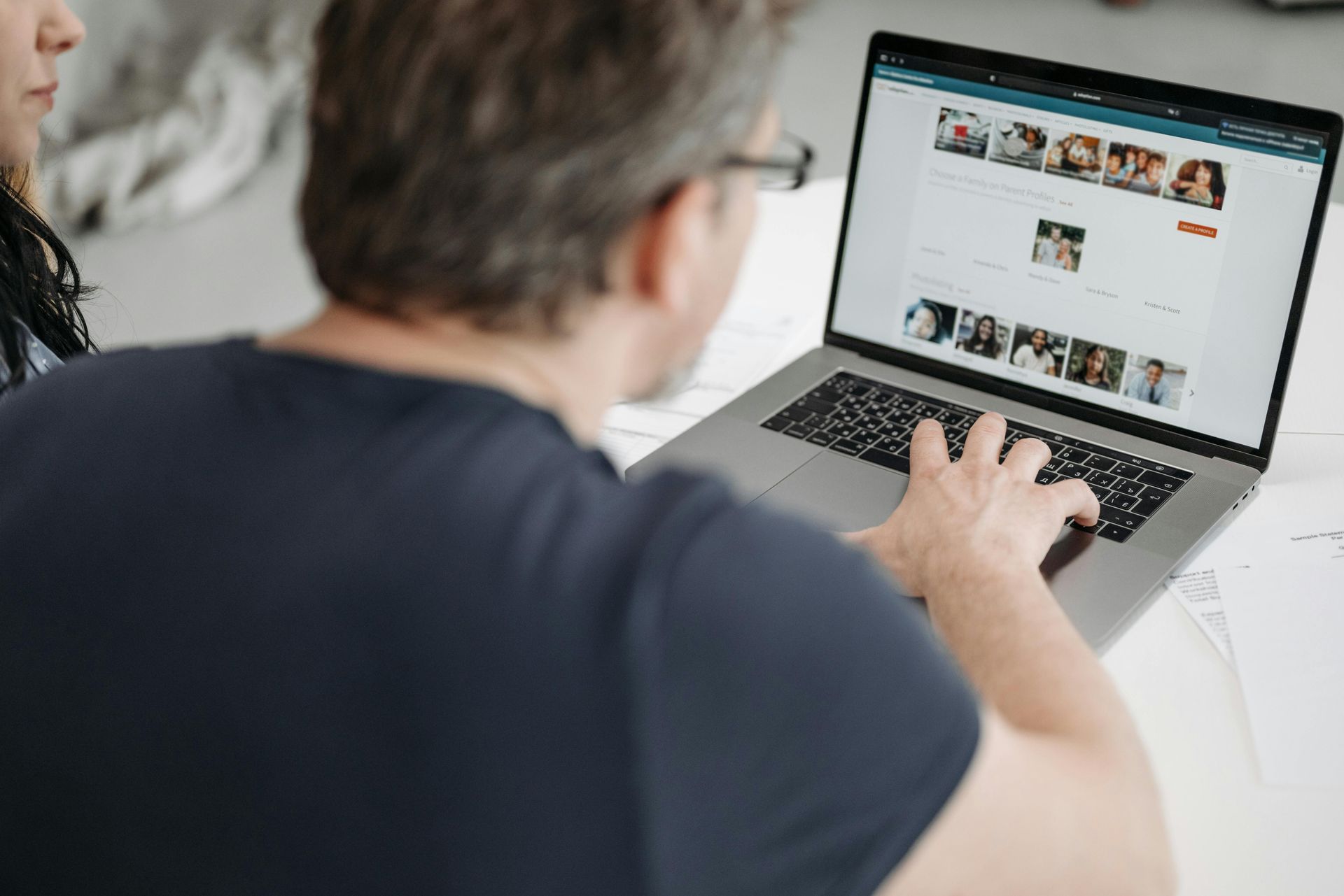 Person using a laptop at a desk, browsing a website with photos on the screen