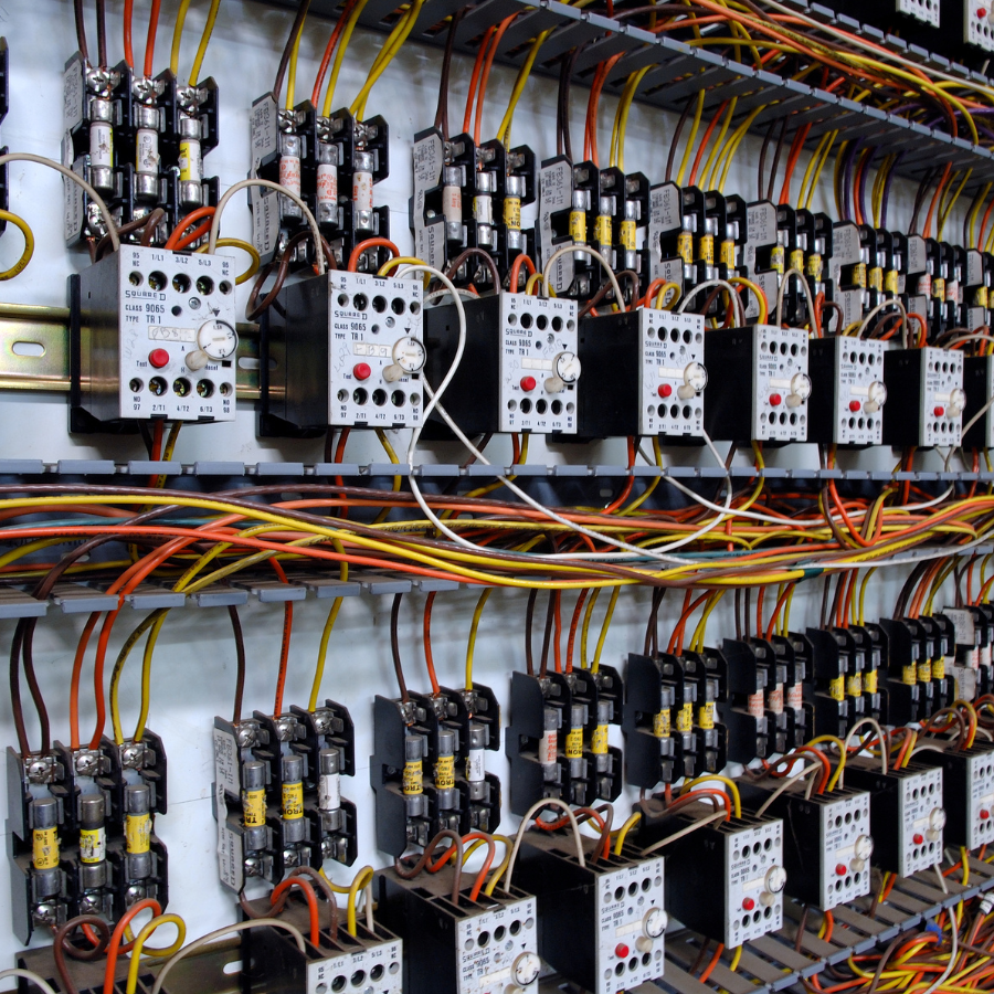 Rows of electrical control components, relays, and colorful wiring inside an industrial panel