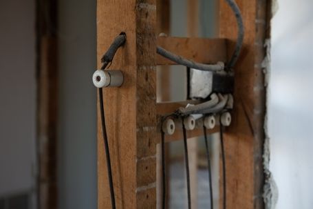 Close-up of exposed electrical wiring and connectors inside a wooden wall opening
