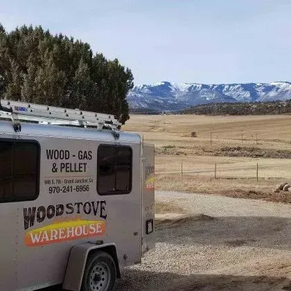 White wood-gas pellet trailer in a rural field with mountains in the background