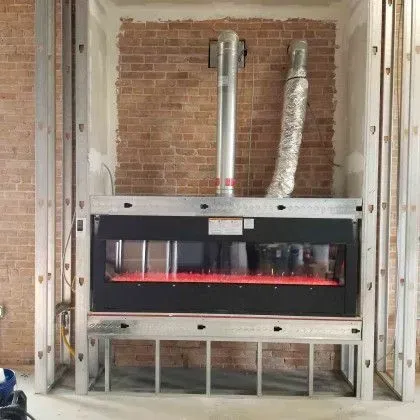 Industrial HVAC unit with exposed brick wall, visible metal ducts, and a red glowing panel inside