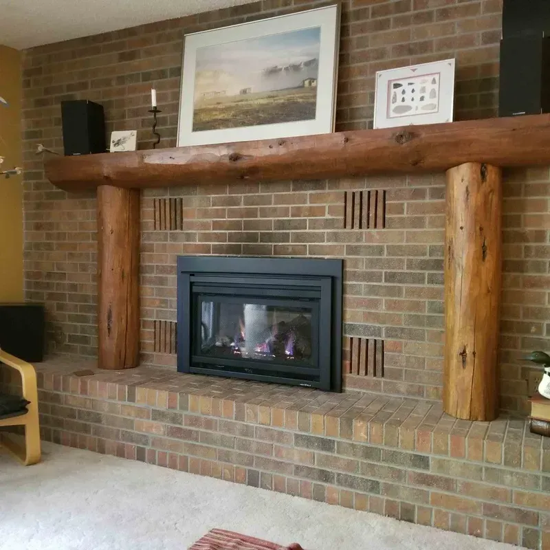 Brick fireplace with wooden mantel and framed art in a living room