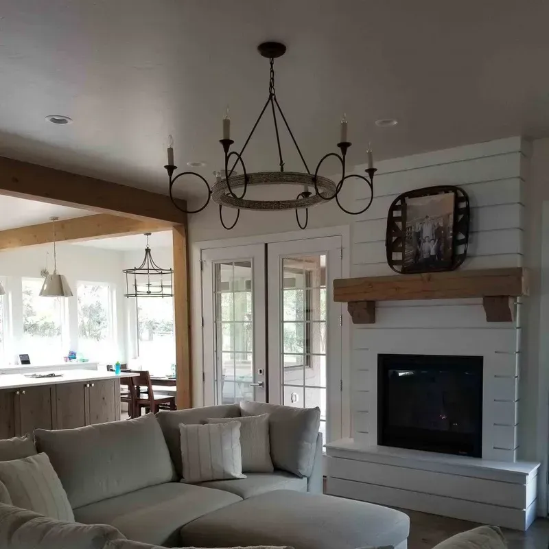 Bright living room with beige sectional, black chandelier, and white shiplap fireplace with mantle