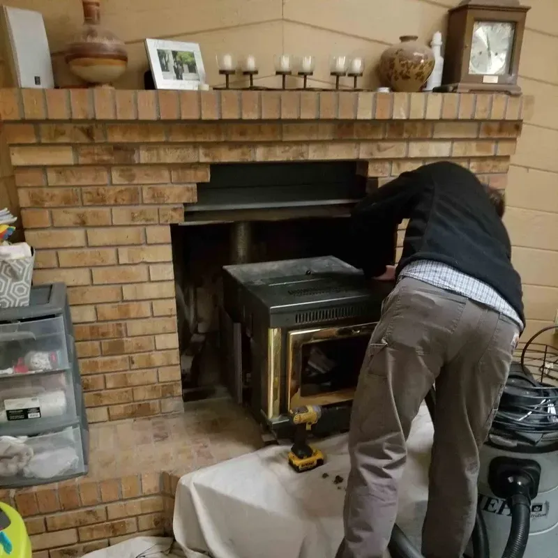 Person repairing a brick fireplace, leaning into the opening with a power drill on a cloth-covered table.