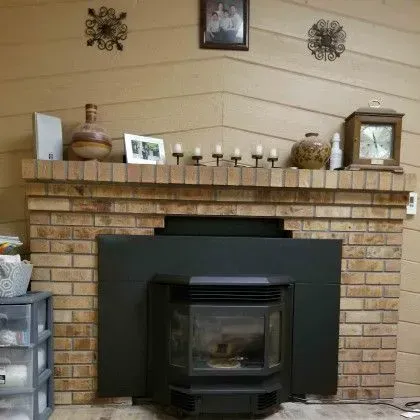 Brick fireplace with black insert and mantel decor in a beige living room