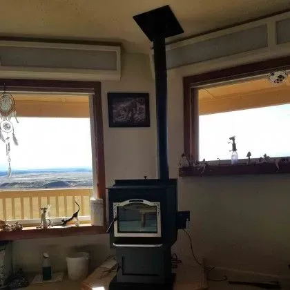 Cozy room with a wood stove, large windows, and a distant ocean view