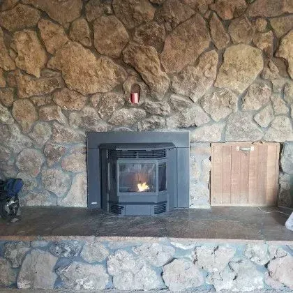 Stone fireplace with a black wood stove insert and a small flame inside