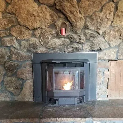 Stone fireplace with a black wood stove insert and a small fire burning inside