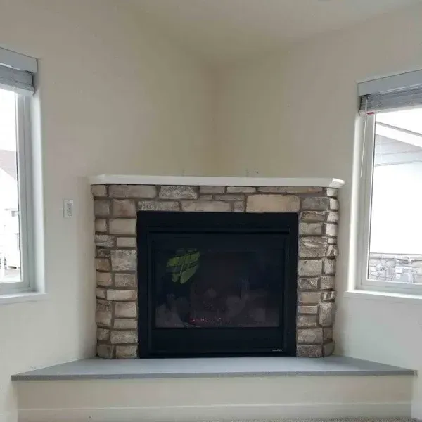 Stone fireplace centered between two windows in a bright room with a built-in bench hearth.