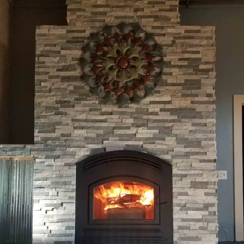 Stone fireplace with a burning fire and a decorative wreath above it