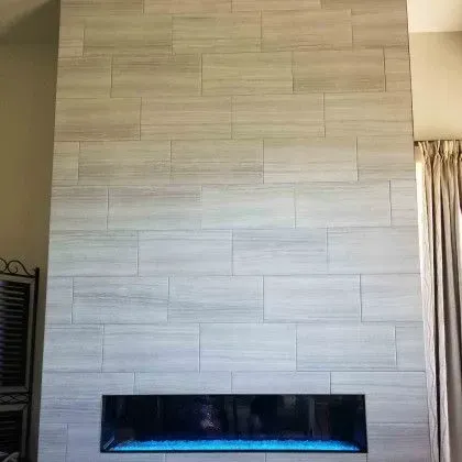 Tall tiled fireplace wall with a long horizontal electric fire in a modern living room