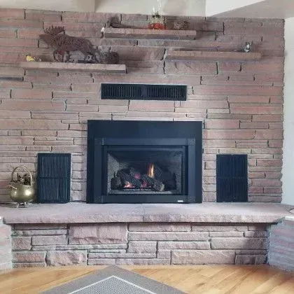 Brick fireplace with black insert, wooden mantle, and decorative items above and beside it