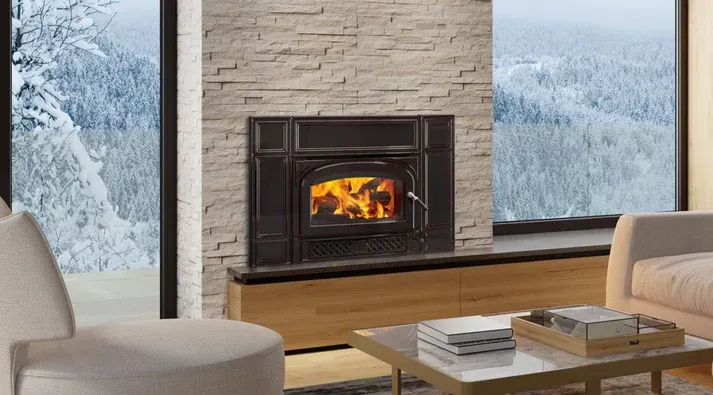 Cozy living room with a brick fireplace, beige sofas, wooden coffee table, and open kitchen beyond.