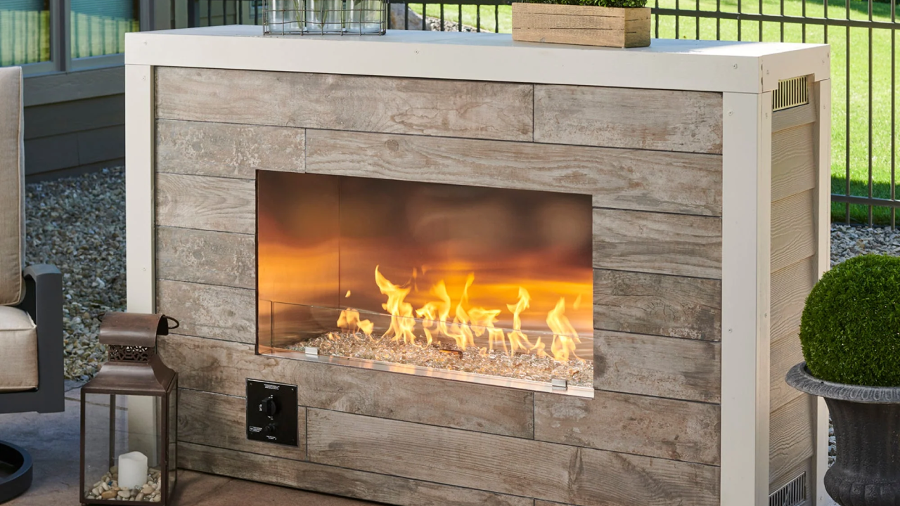 Modern outdoor stone fire pit with a glowing flame in a patio setting