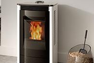 Modern pellet stove with visible flame beside a glass container of pellets and tool.