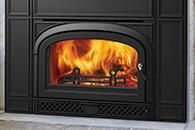 Black fireplace with a bright orange fire burning behind glass doors