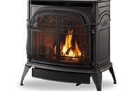 Black cast-iron fireplace stove with a fire burning behind a glass front.