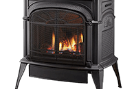 Black cast-iron fireplace stove with a fire burning behind a mesh screen