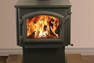 Black wood-burning stove with a bright fire burning inside in a room