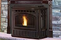 Black wood-burning stove with a small flame, set against a stone wall