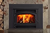Lit fireplace insert with bright orange flames in a stone surround