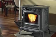 Lit black cast-iron wood stove with visible flames in a cozy room with hardwood floor