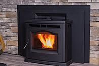 Black fireplace insert with bright orange flames set in a stone wall