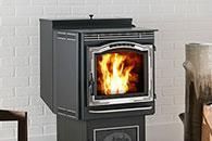 Black wood stove with a bright fire burning in front of a white brick wall