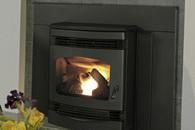 Lit black wood stove with a visible fire inside, set in a gray tiled fireplace.