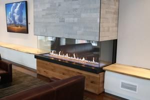 Modern living room with a long wall-mounted fireplace, wood paneling, and framed wall art