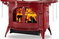 Red cast-iron wood-burning stove with a glowing fire behind glass doors