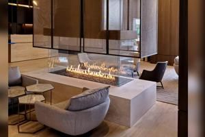 Modern lounge with a long glass fire table, upholstered chairs, and warm wood accents