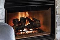 Lit fireplace with glowing logs and flames in a stone surround