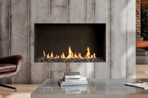 Modern fireplace with small flames in a concrete wall above a glass coffee table and stacked books