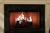 Lit fireplace with flames burning in a mantel surrounded by dark stone.