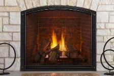 Fire burning in a brick fireplace with a black arched metal screen.