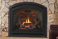 Stone fireplace with a black arched insert and a small fire burning inside.