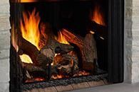 Burning fire in a stone fireplace with logs and bright orange flames