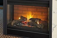 Fire burning in a glass-front fireplace with glowing logs and brick surround