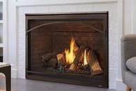 Lit fireplace with flames inside a brown mantel in a living room