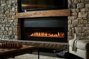 Stone fireplace with a long gas flame, wood mantel, and beige sofa in a cozy living room