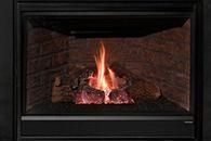 A lit gas fireplace with orange flames and glowing logs inside a black frame
