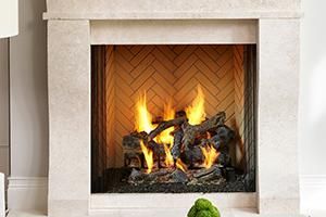 Lit fireplace with bright flames and dark logs in a white mantel.