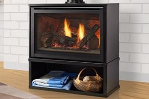 Black electric fireplace cabinet with visible flame, folded towels, and a basket on a wood floor